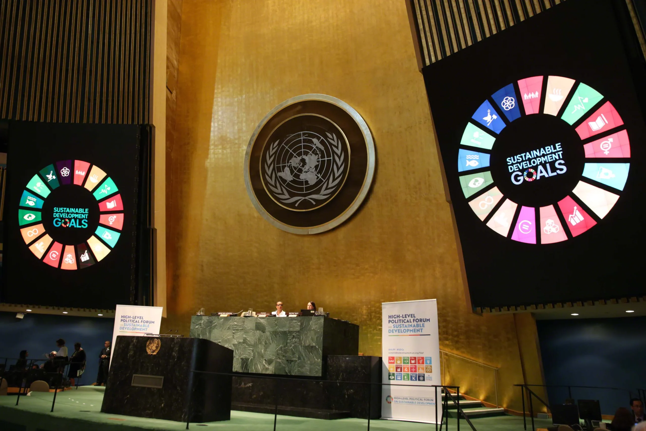 Impressive photo of two giant monitors showing the SDGs wheel next to the UN emblem inside of the UN Headquarters
