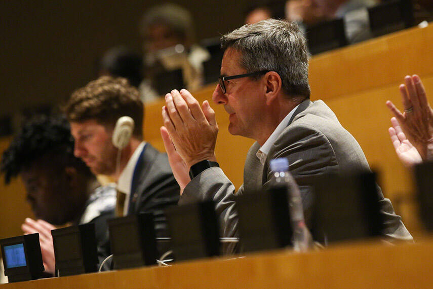 Focus on a man sitting in the UN headquarters' plenary applauding