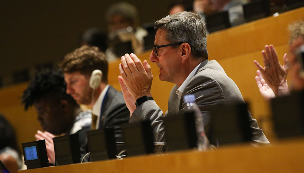 Focus on a man sitting in the UN headquarters' plenary applauding