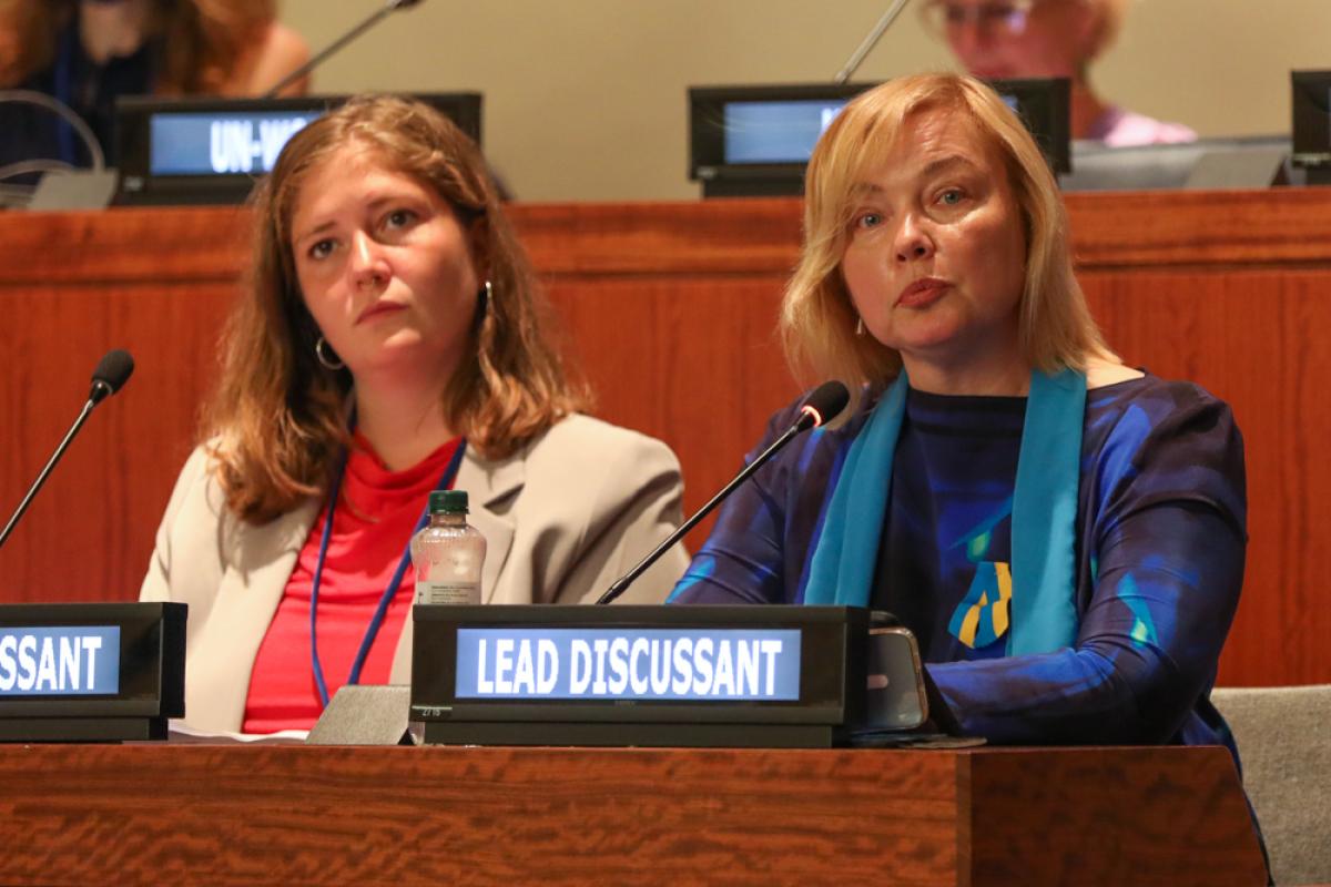 Two women from civil society sitting behind microphones at the UN. One of them is wearing the Women's Major Group's cress code, looking determined into the camera.